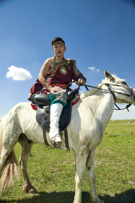 草原那达慕大会上骑着马的蒙古人图片