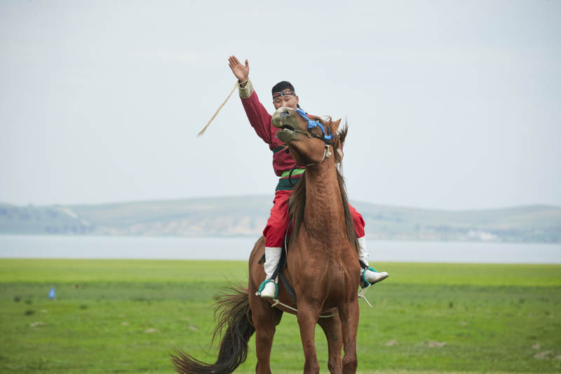 草原那达慕大会上骑着马的蒙古人图片