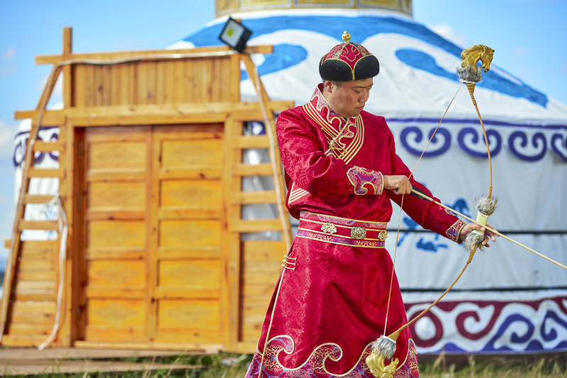 蒙古包前身穿蒙古族饰手持弓箭的蒙族汉子图片