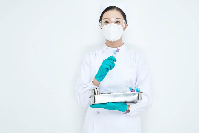 身穿护士服手抱化验托盘的年轻女护士图片