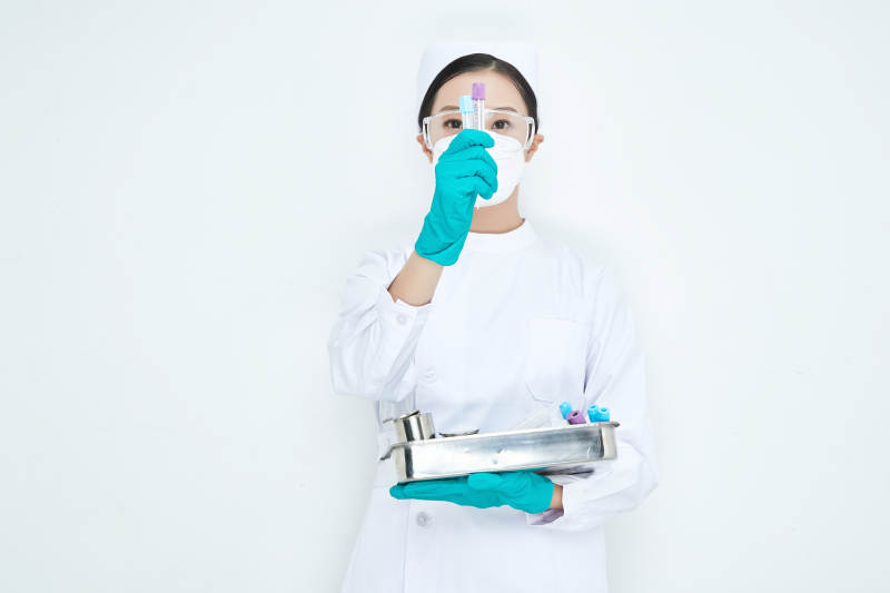 身穿护士服手抱化验托盘的年轻女护士图片