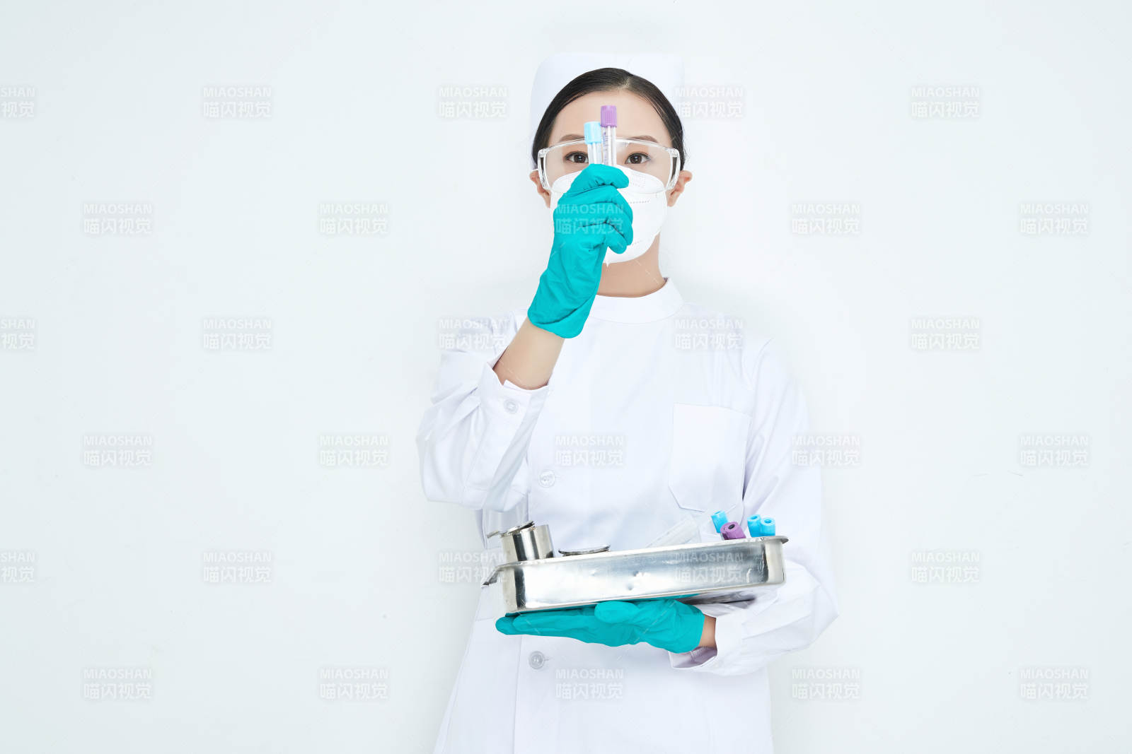 身穿护士服手抱化验托盘的年轻女护士图片