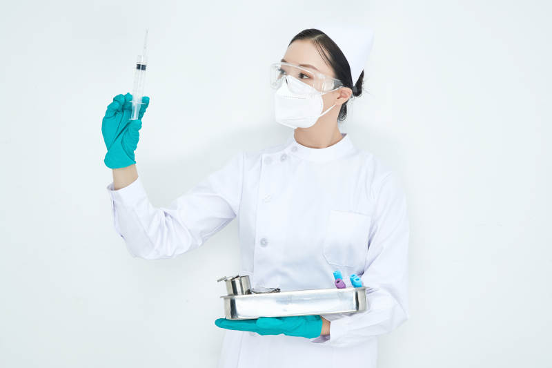 身穿护士服手抱化验托盘的年轻女护士图片