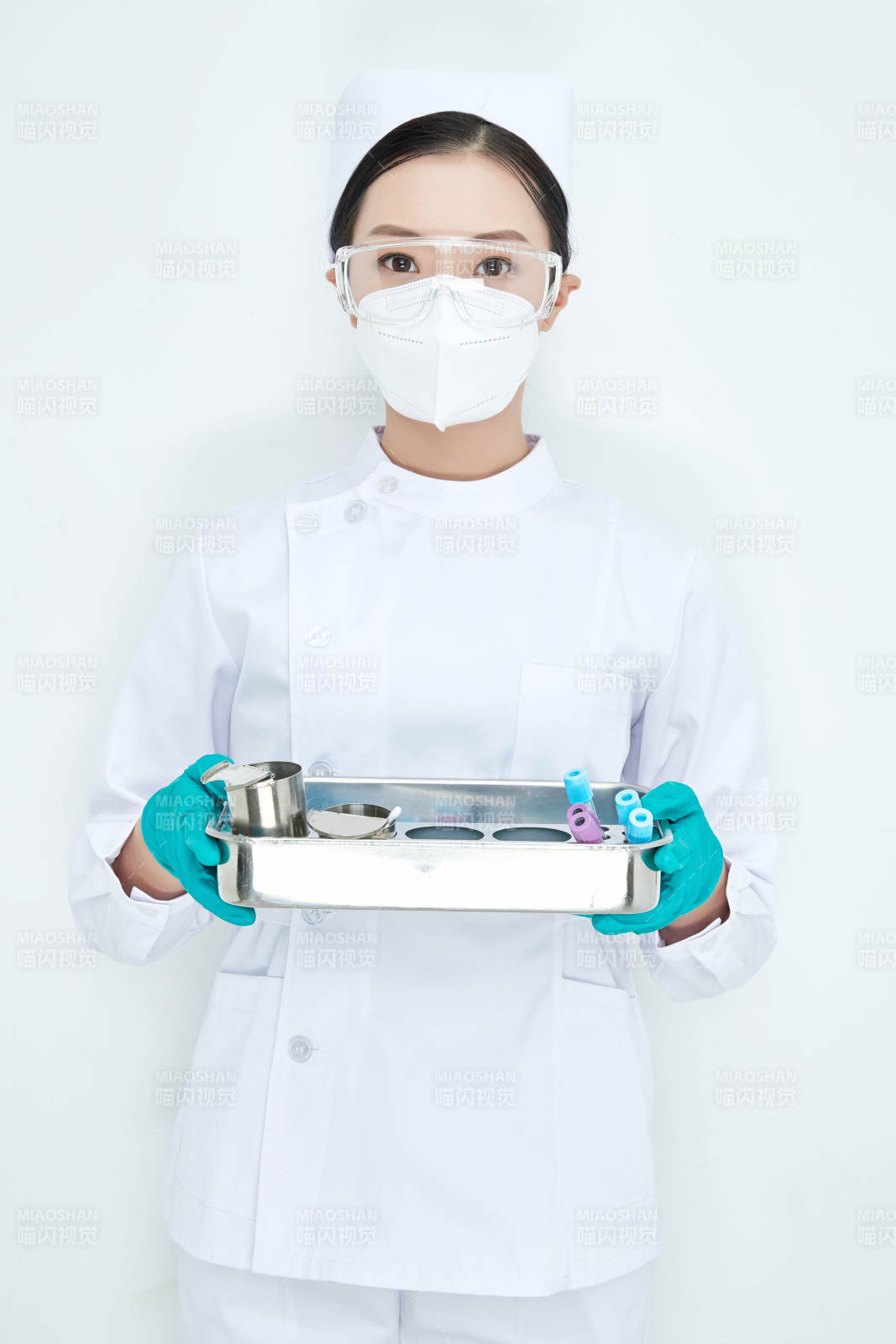 身穿护士服手抱化验托盘的年轻女护士图片