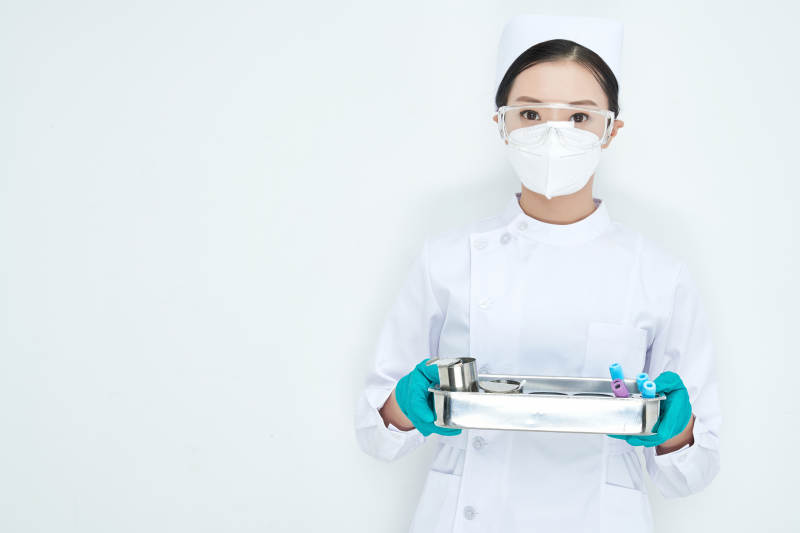 身穿护士服手抱化验托盘的年轻女护士图片