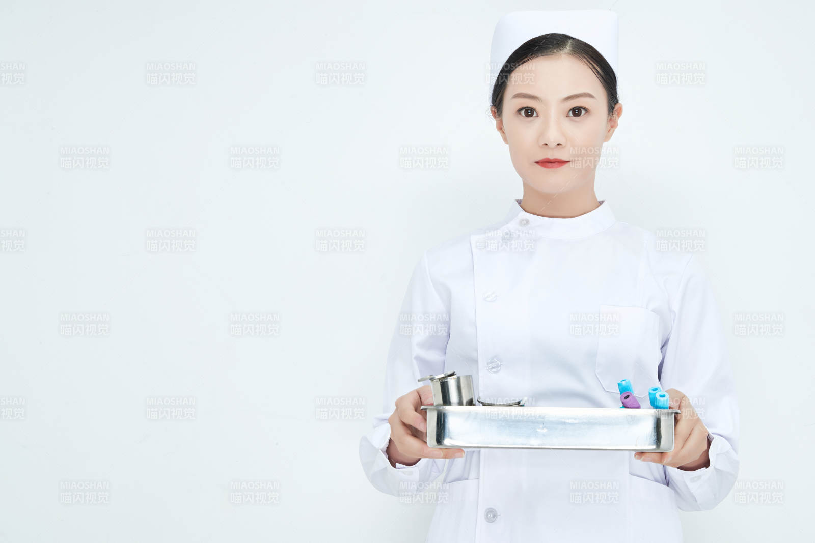 身穿护士服手抱化验托盘的年轻女护士图片