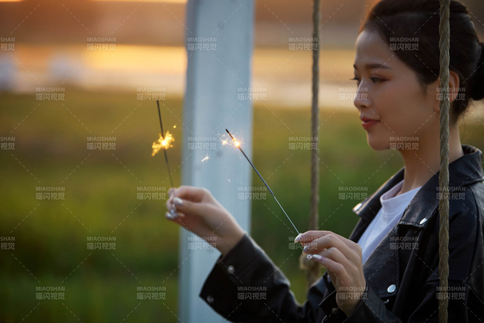 夕阳下湖畔秋千上燃放仙女棒的可爱少女图片