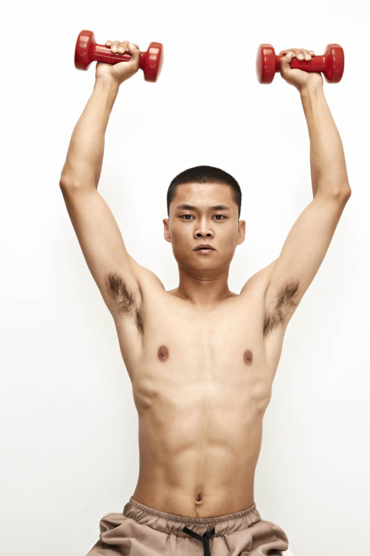 使用哑铃进行健身锻炼的亚洲男性图片