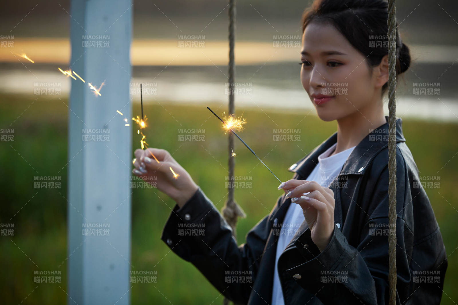 夕阳下湖畔秋千上燃放仙女棒的可爱少女图片