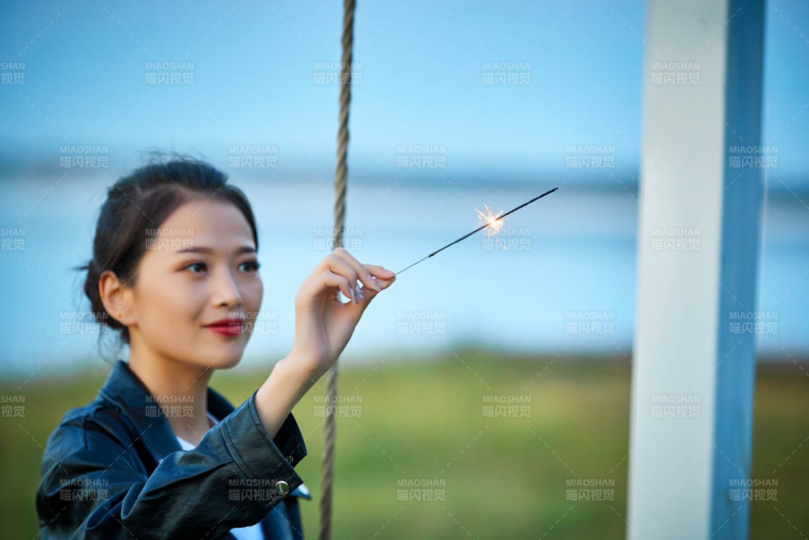夕阳下湖畔秋千上燃放仙女棒的可爱少女图片