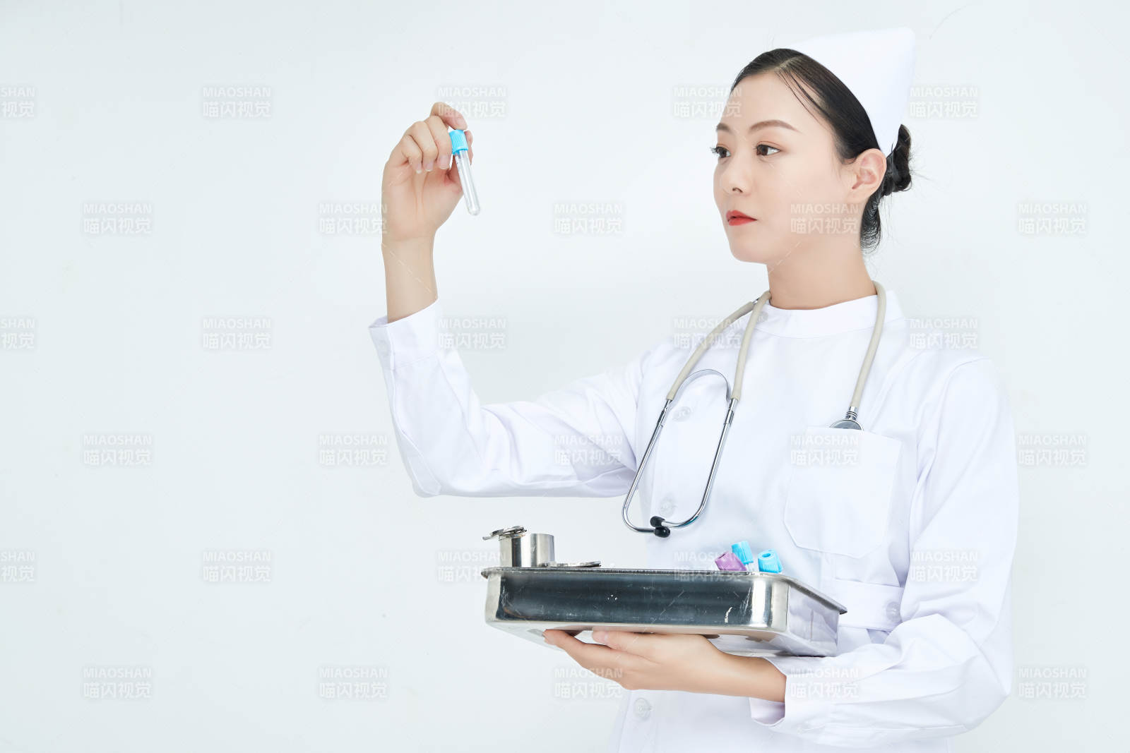 身穿护士服手抱化验托盘的年轻女护士图片