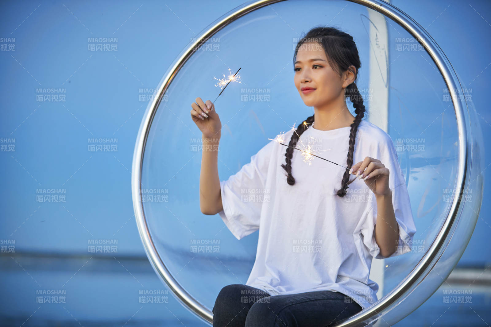 傍晚湖畔透明秋千上燃放仙女棒的可爱少女图片