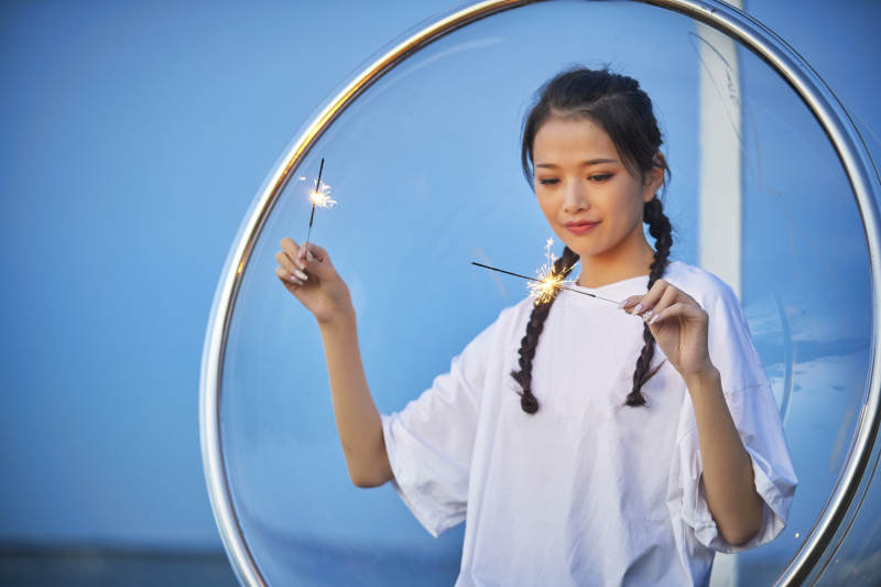 傍晚湖畔透明秋千上燃放仙女棒的可爱少女图片