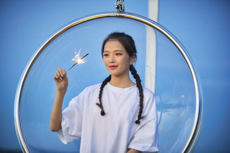 傍晚湖畔透明秋千上燃放仙女棒的可爱少女图片