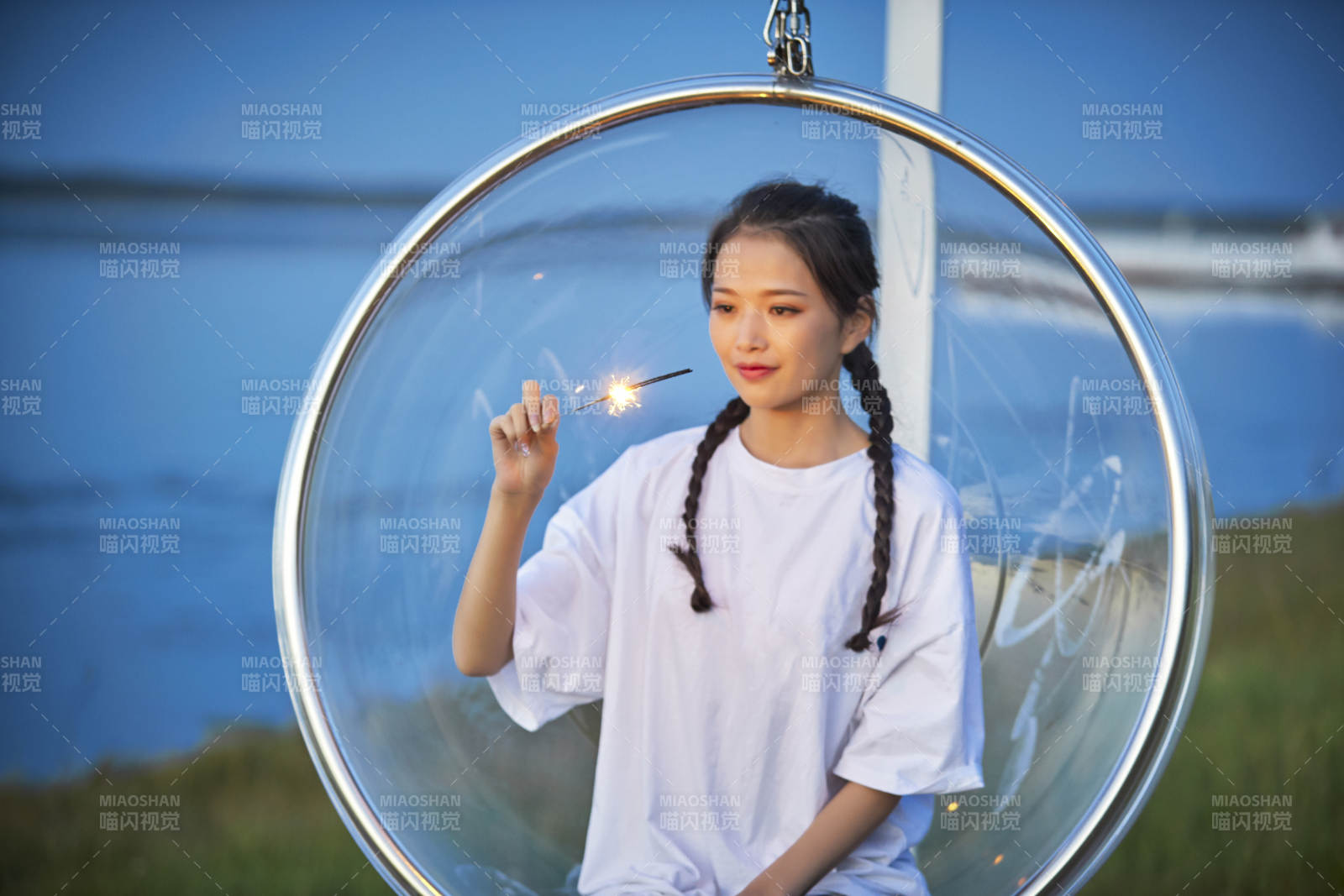 傍晚湖畔透明秋千上燃放仙女棒的可爱少女图片