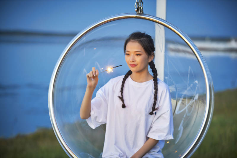 傍晚湖畔透明秋千上燃放仙女棒的可爱少女图片