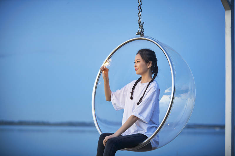 傍晚湖畔透明秋千上燃放仙女棒的可爱少女图片