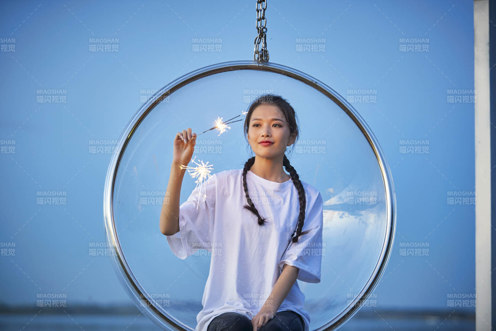 傍晚湖畔透明秋千上燃放仙女棒的可爱少女图片