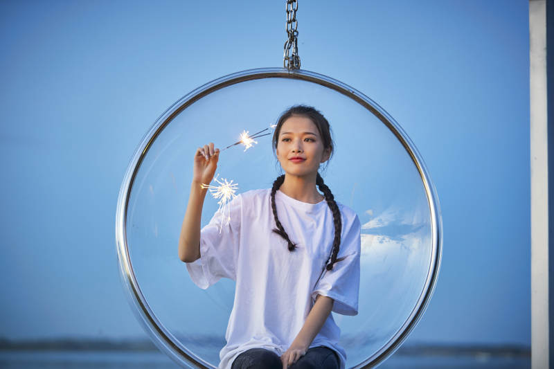 傍晚湖畔透明秋千上燃放仙女棒的可爱少女图片