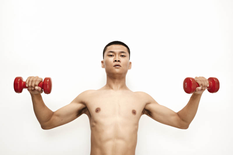 使用哑铃进行健身锻炼的亚洲男性图片