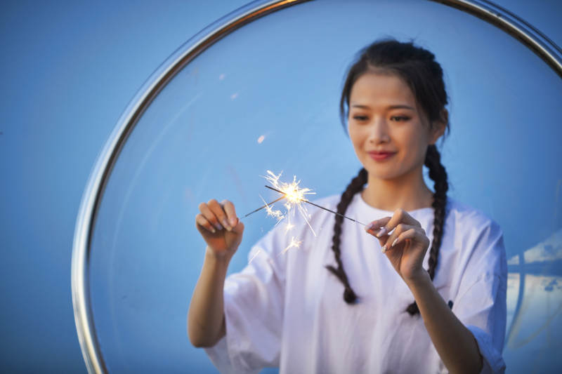 傍晚湖畔透明秋千上燃放仙女棒的可爱少女图片