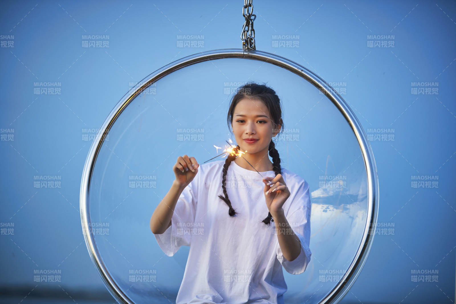 傍晚湖畔透明秋千上燃放仙女棒的可爱少女图片