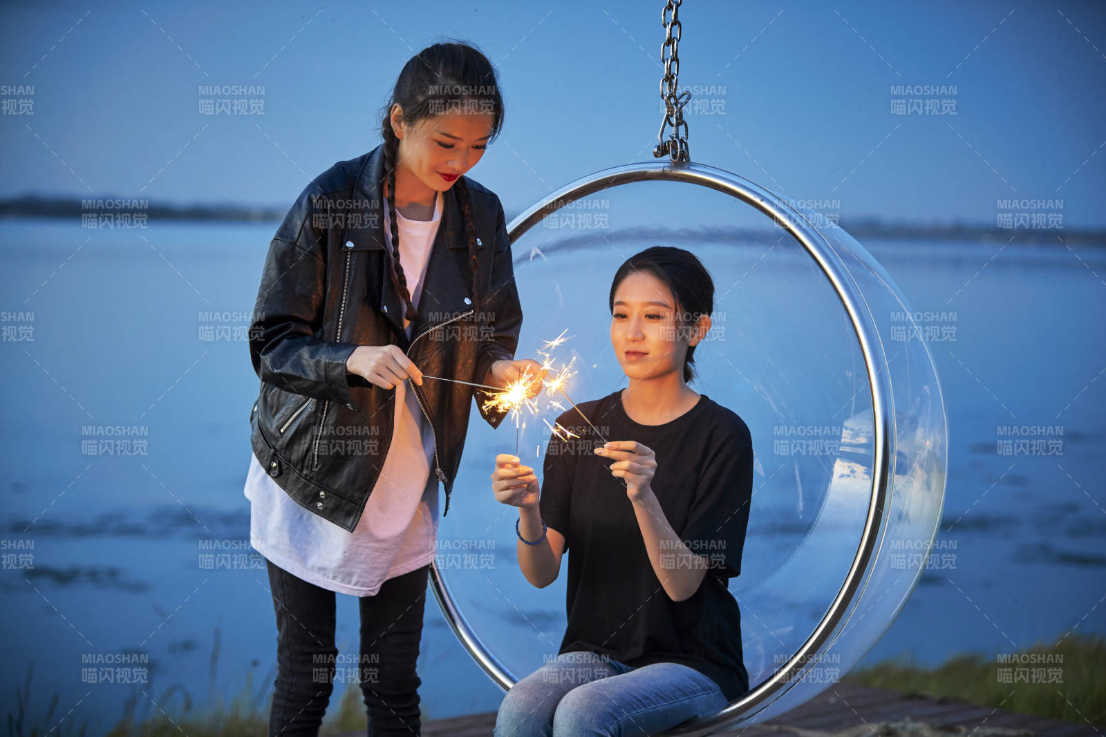 傍晚湖畔透明秋千上燃放仙女棒的可爱少女图片