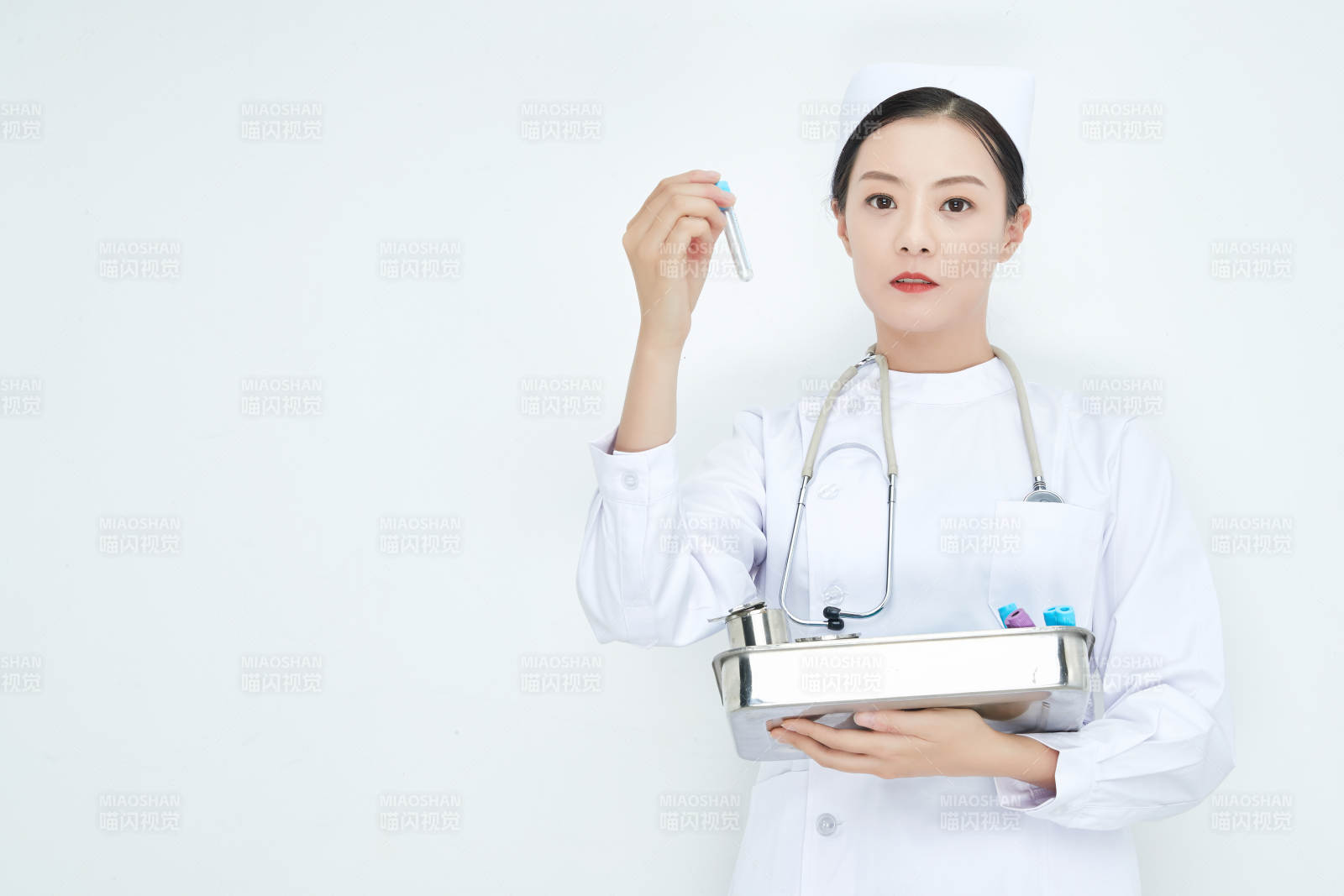 身穿护士服手抱化验托盘的年轻女护士图片