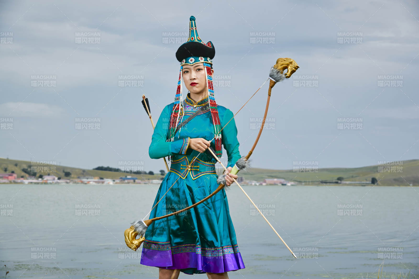 草原湖畔身穿蒙古族饰手持弓箭的蒙族少女图片