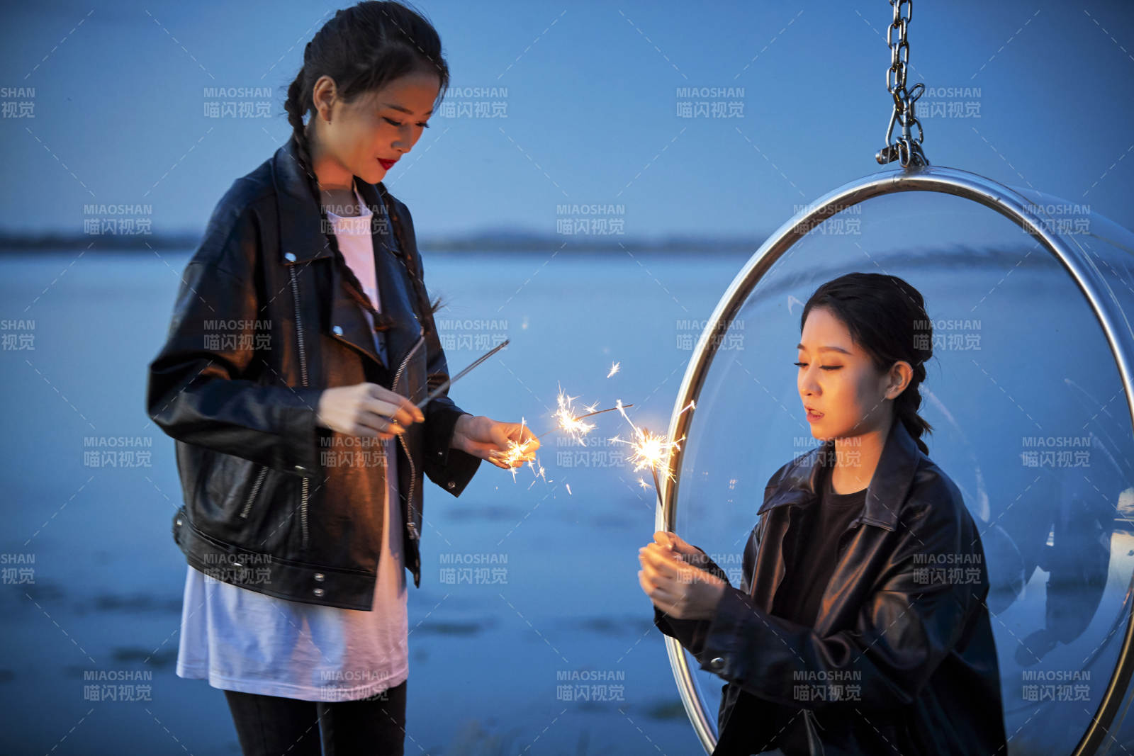 傍晚湖畔透明秋千上燃放仙女棒的可爱少女图片