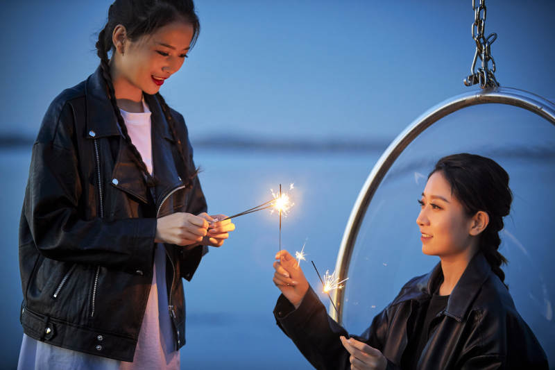 傍晚湖畔透明秋千上燃放仙女棒的可爱少女图片