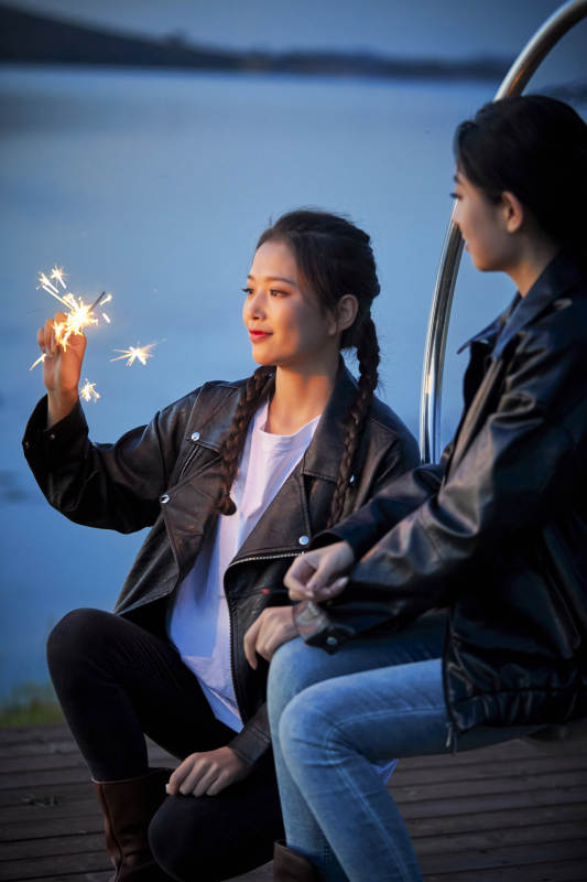 傍晚湖畔透明秋千上燃放仙女棒的可爱少女图片