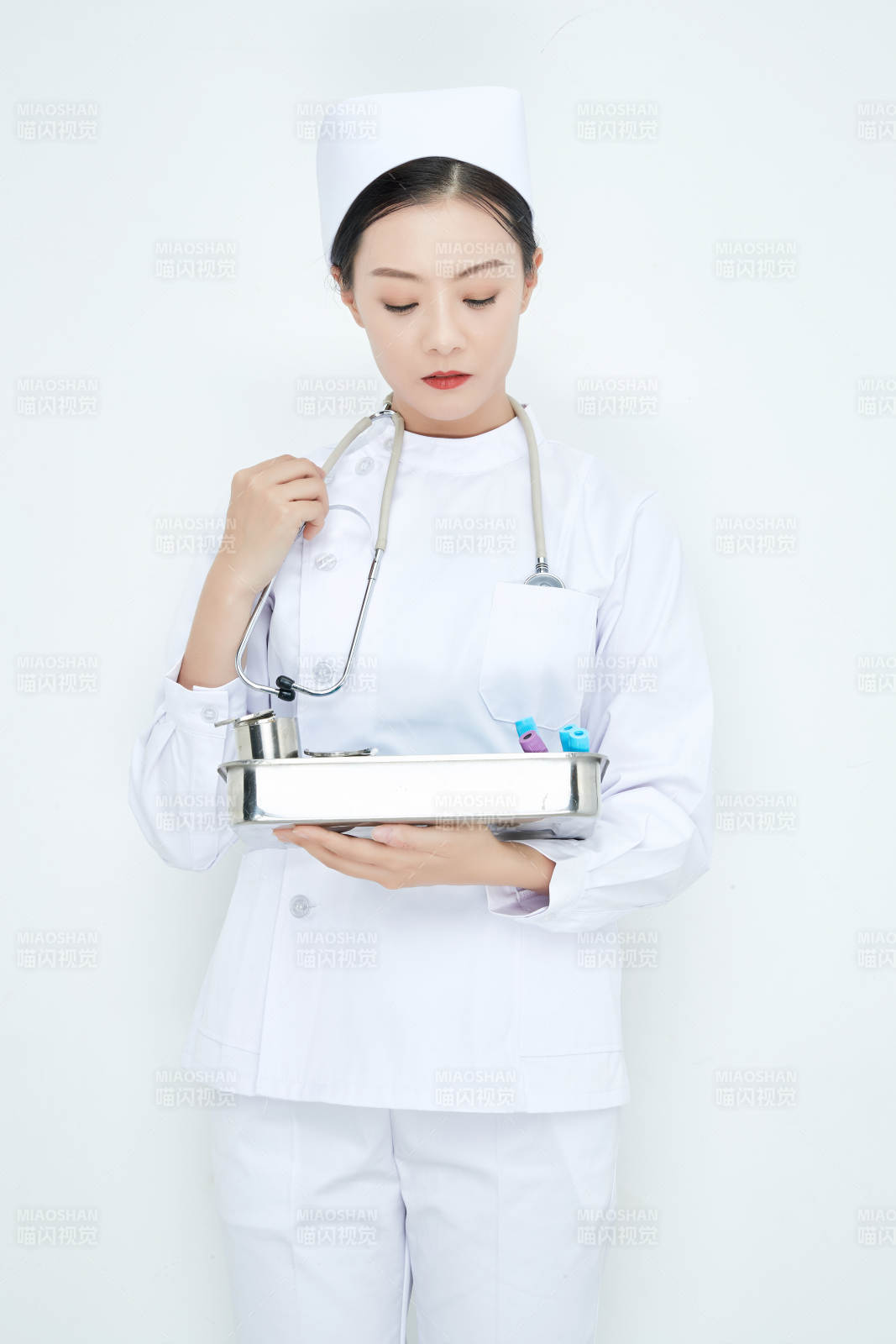 身穿护士服手抱化验托盘的年轻女护士图片
