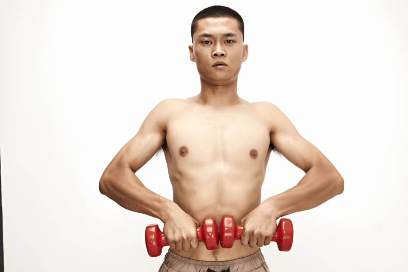 使用哑铃进行健身锻炼的亚洲男性图片