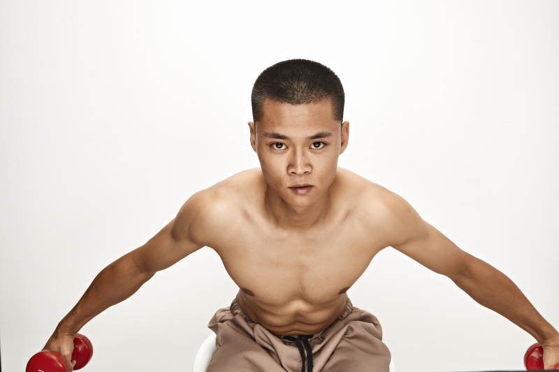 使用哑铃进行健身锻炼的亚洲男性图片
