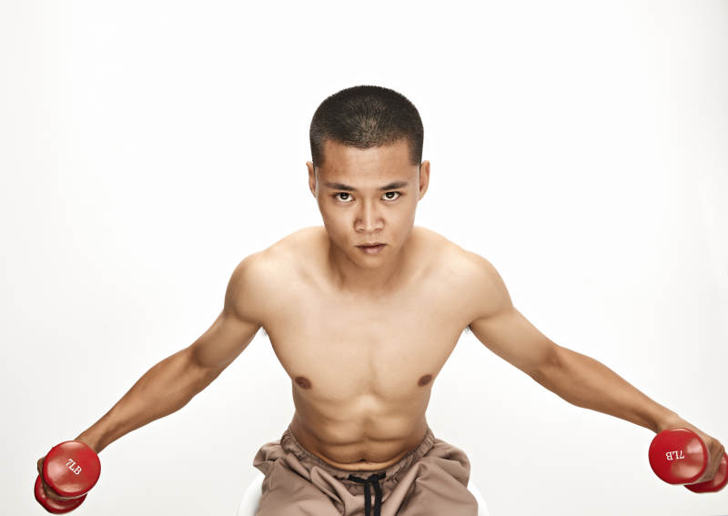 使用哑铃进行健身锻炼的亚洲男性图片