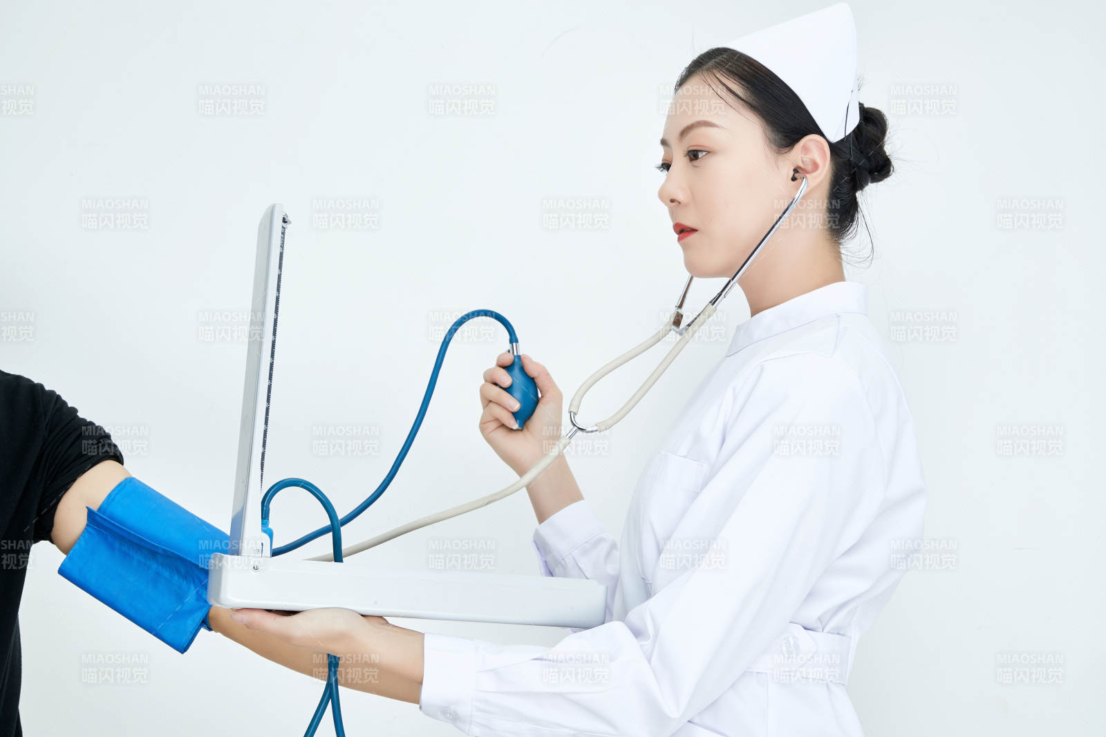 白色背景下手持血压计测量血压的医生图片