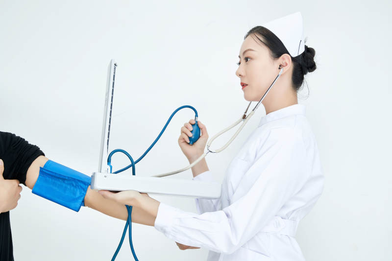 白色背景下手持血压计测量血压的医生图片