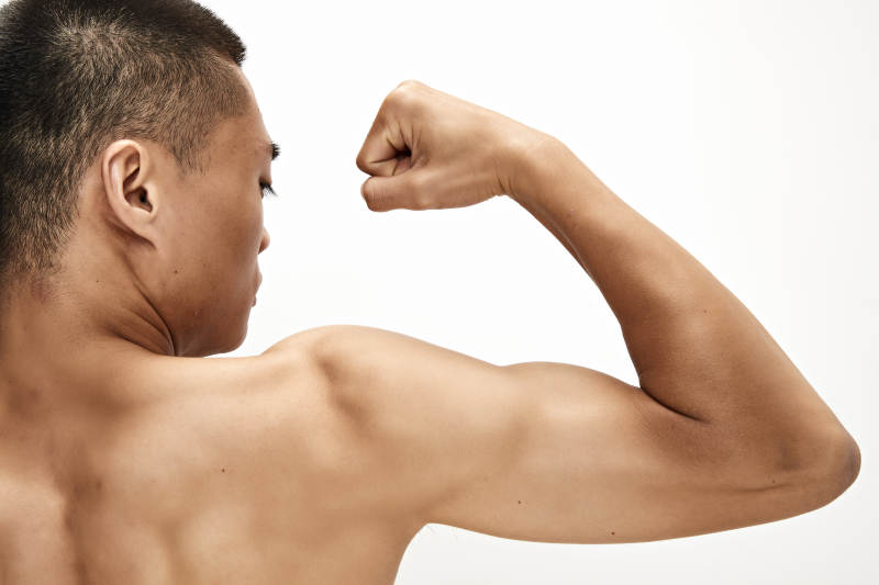 白色背景下展示肱二头肌的亚洲健身男性图片