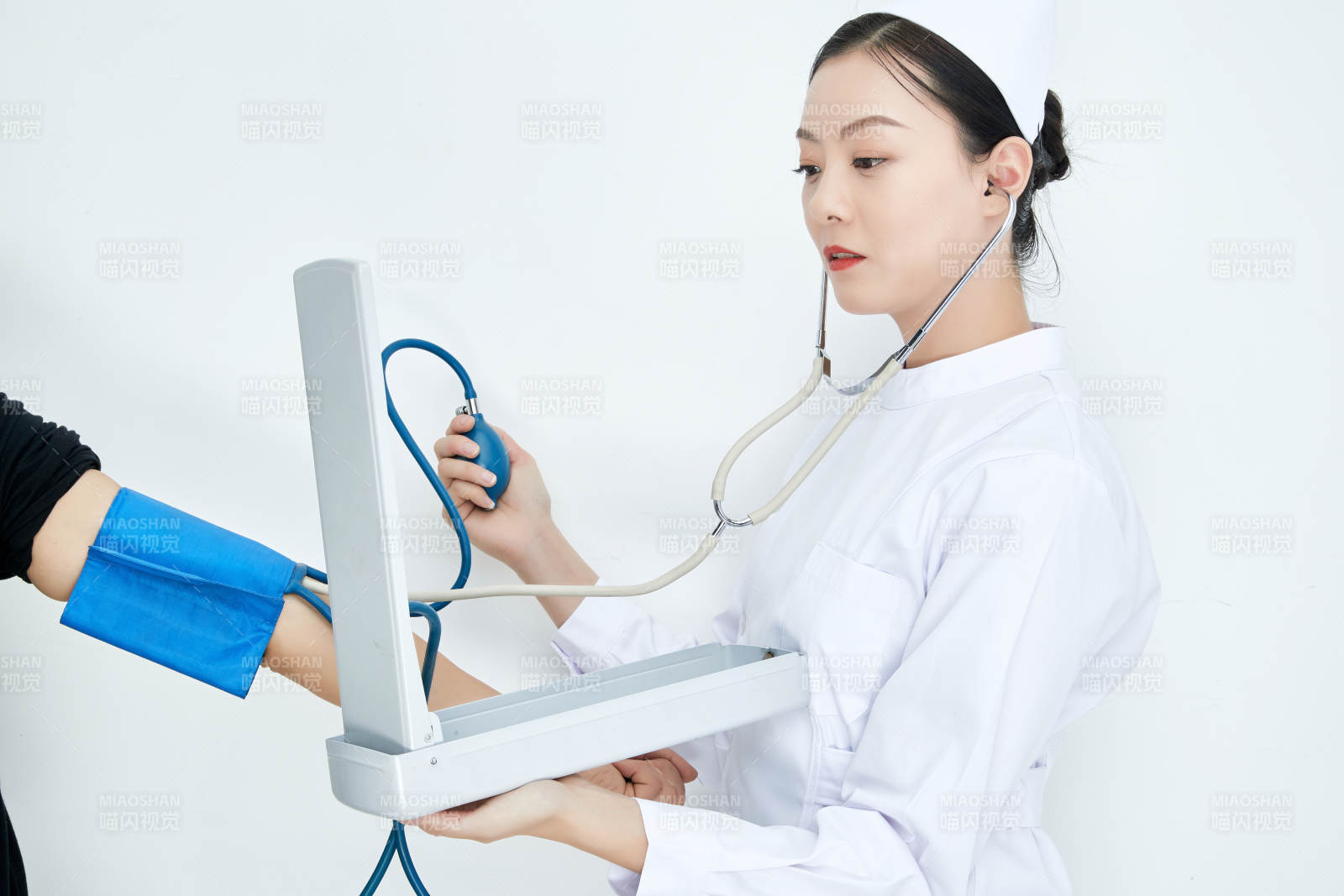 白色背景下手持血压计测量血压的医生图片