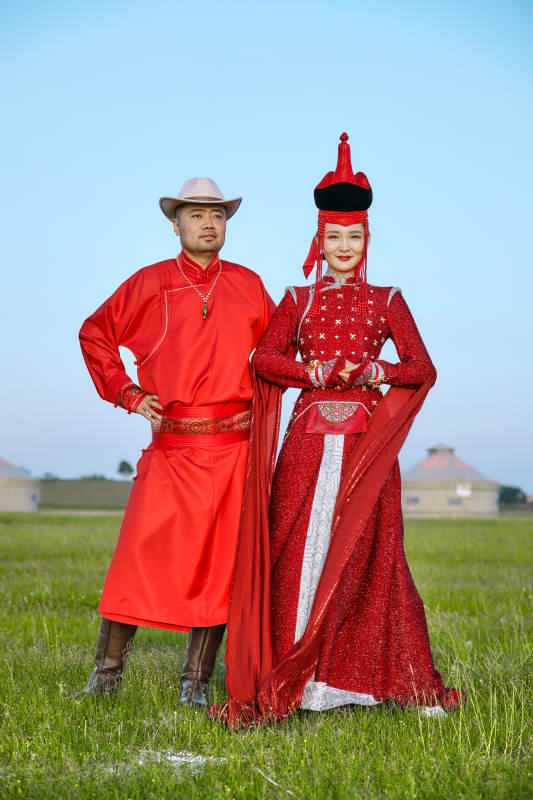 草原上蒙古包前穿蒙古族传统服饰的年轻夫妻图片