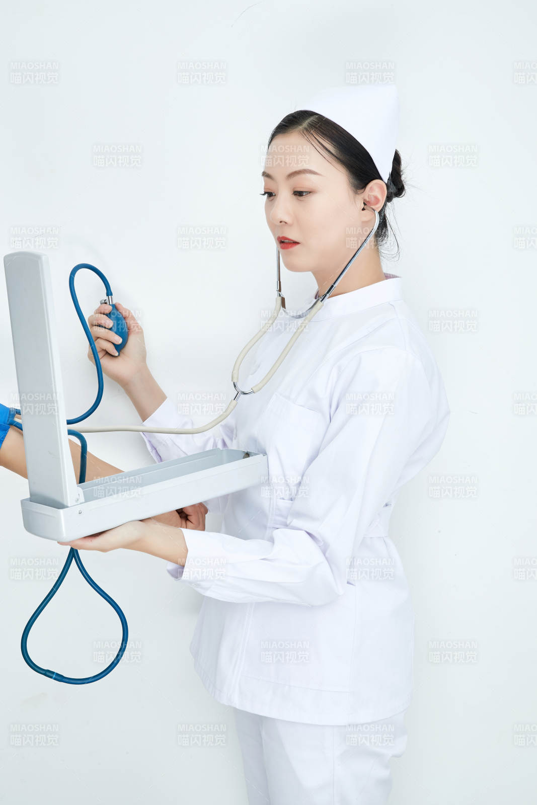 白色背景下手持血压计测量血压的医生图片