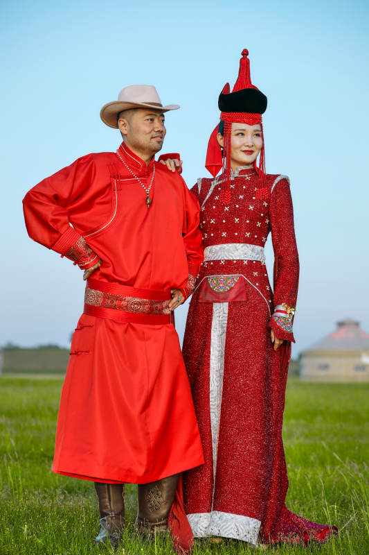 草原上蒙古包前穿蒙古族传统服饰的年轻夫妻图片