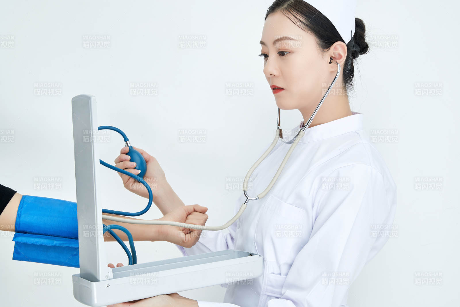 白色背景下手持血压计测量血压的医生图片