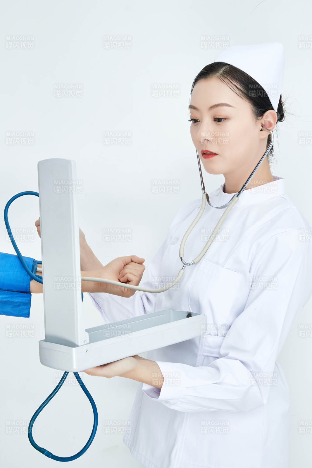 白色背景下手持血压计测量血压的医生图片