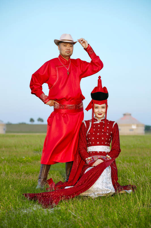 草原上蒙古包前穿蒙古族传统服饰的年轻夫妻图片