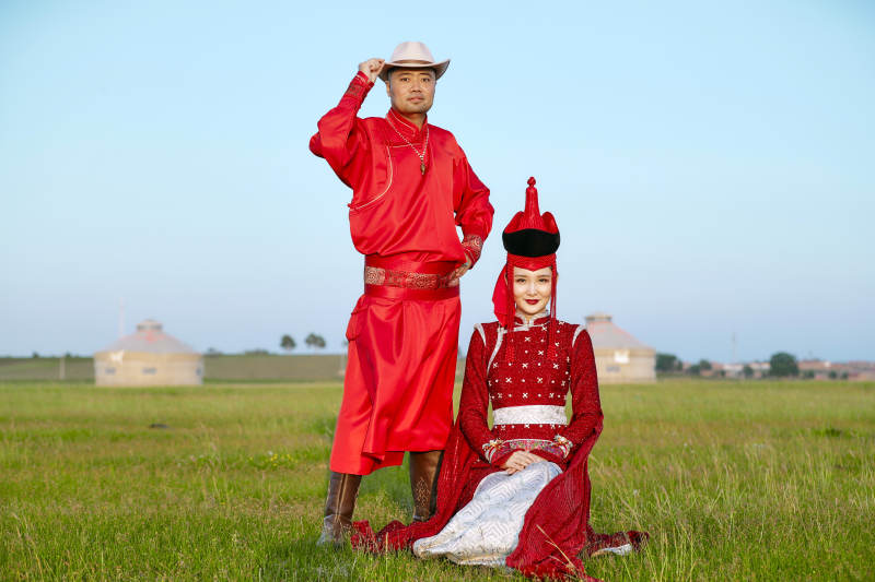 草原上蒙古包前穿蒙古族传统服饰的年轻夫妻图片