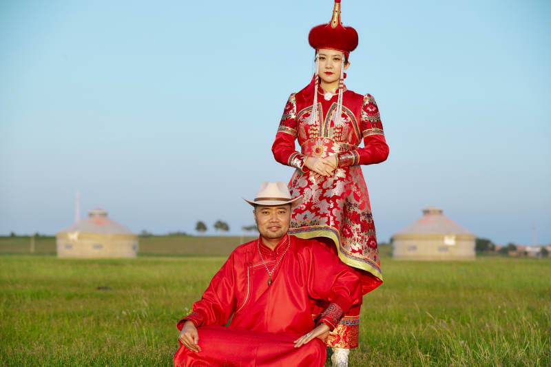 草原上蒙古包前穿蒙古族传统服饰的年轻夫妻图片