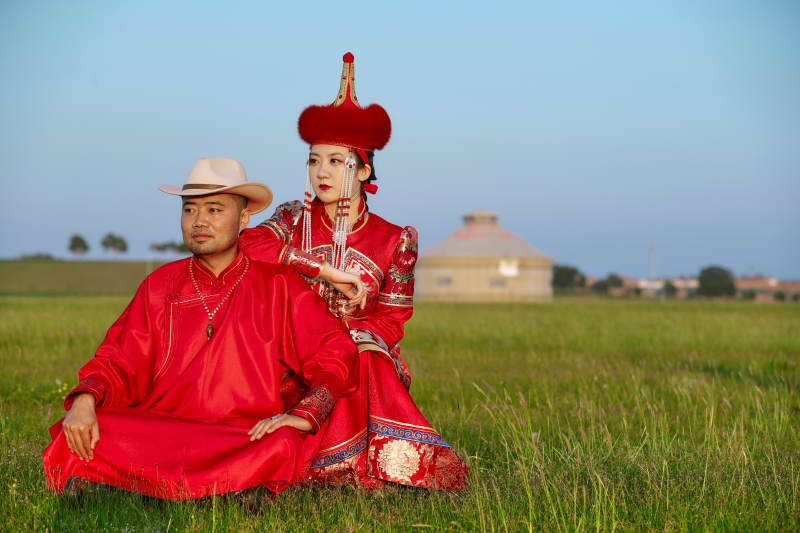 草原上蒙古包前穿蒙古族传统服饰的年轻夫妻图片