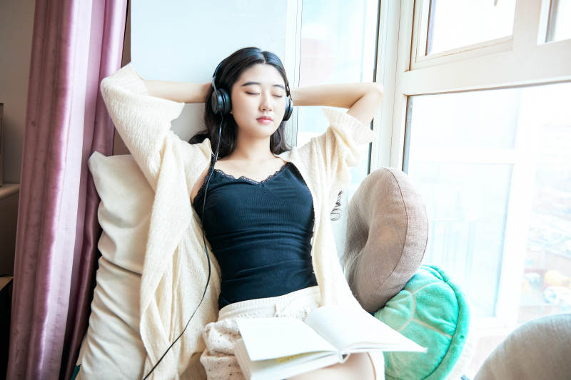 躺在舒适的飘窗上听音乐看书玩手机的女孩图片